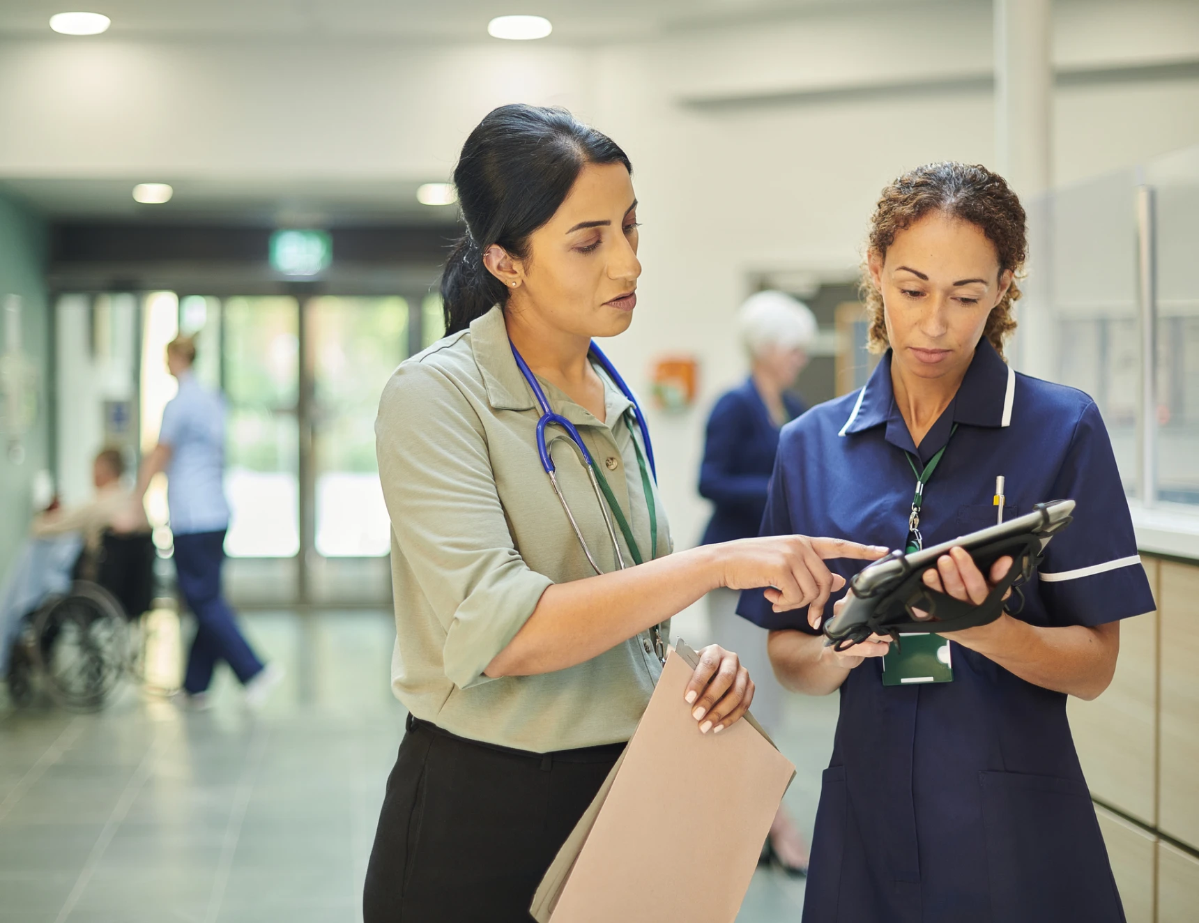 Healthcare staff collaborating in hospital corridor.